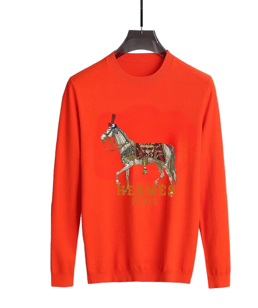 Orange sweater with embroidered horse design on a hanger against a marble wall.